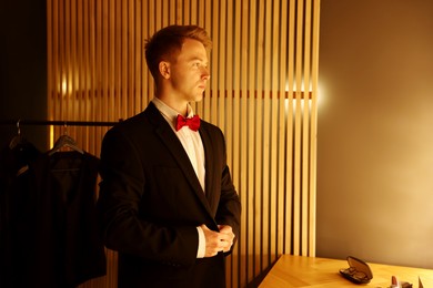 Photo of Handsome man with bow tie getting ready indoors