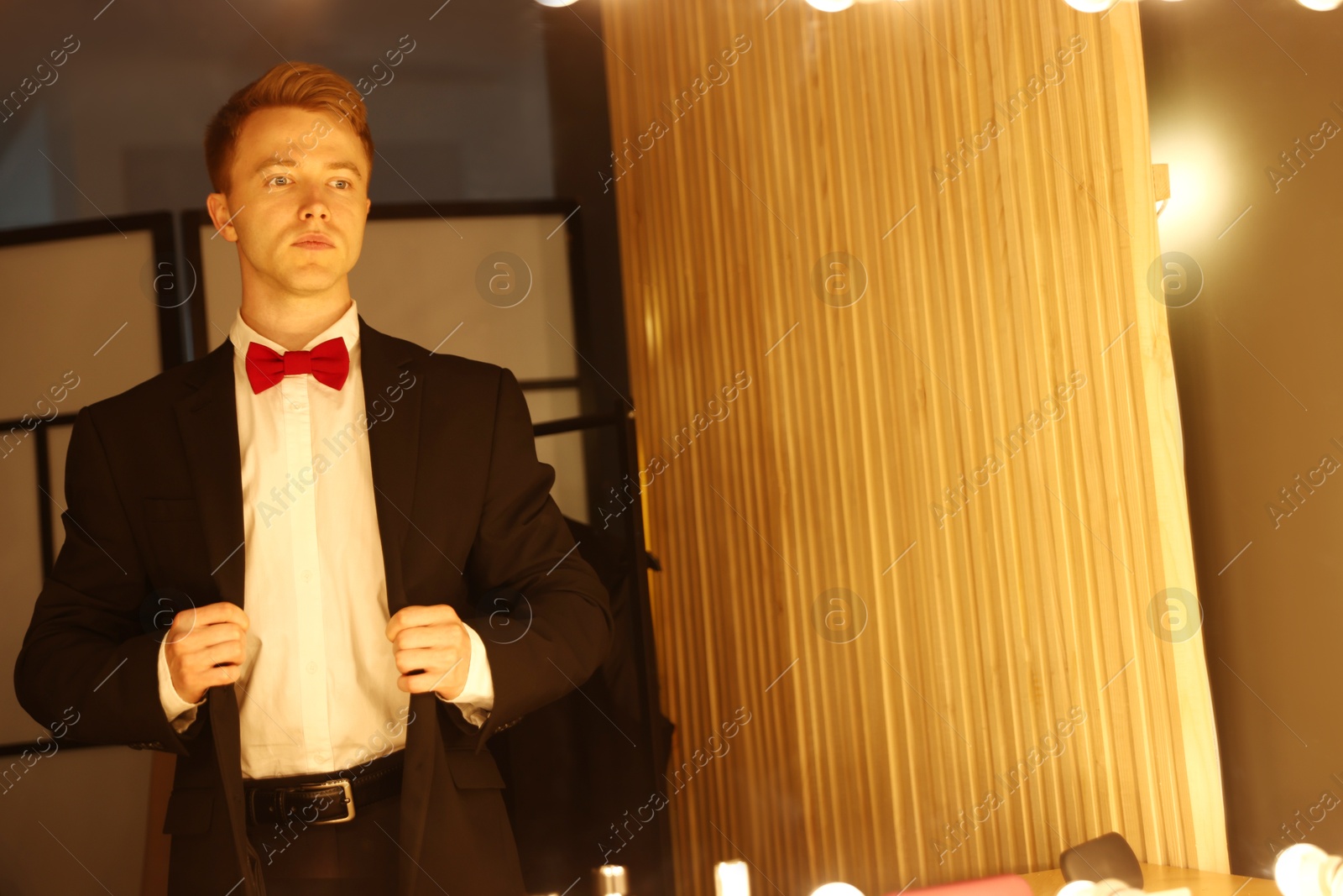 Handsome man getting ready near mirror indoors Photo of Handsome man getting ready near mirror indoors