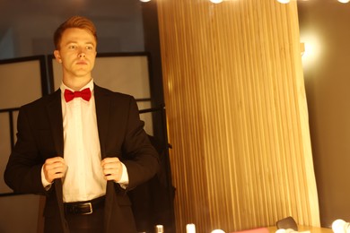 Photo of Handsome man getting ready near mirror indoors