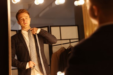 Photo of Man with necktie getting ready near mirror indoors