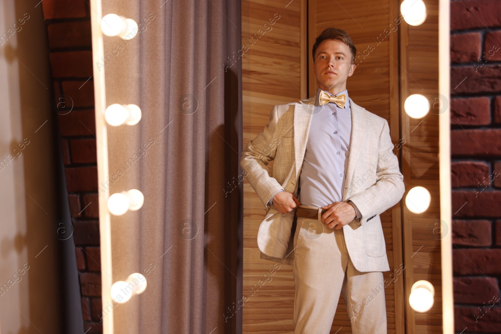 Handsome man getting ready near mirror indoors Photo of Handsome man getting ready near mirror indoors