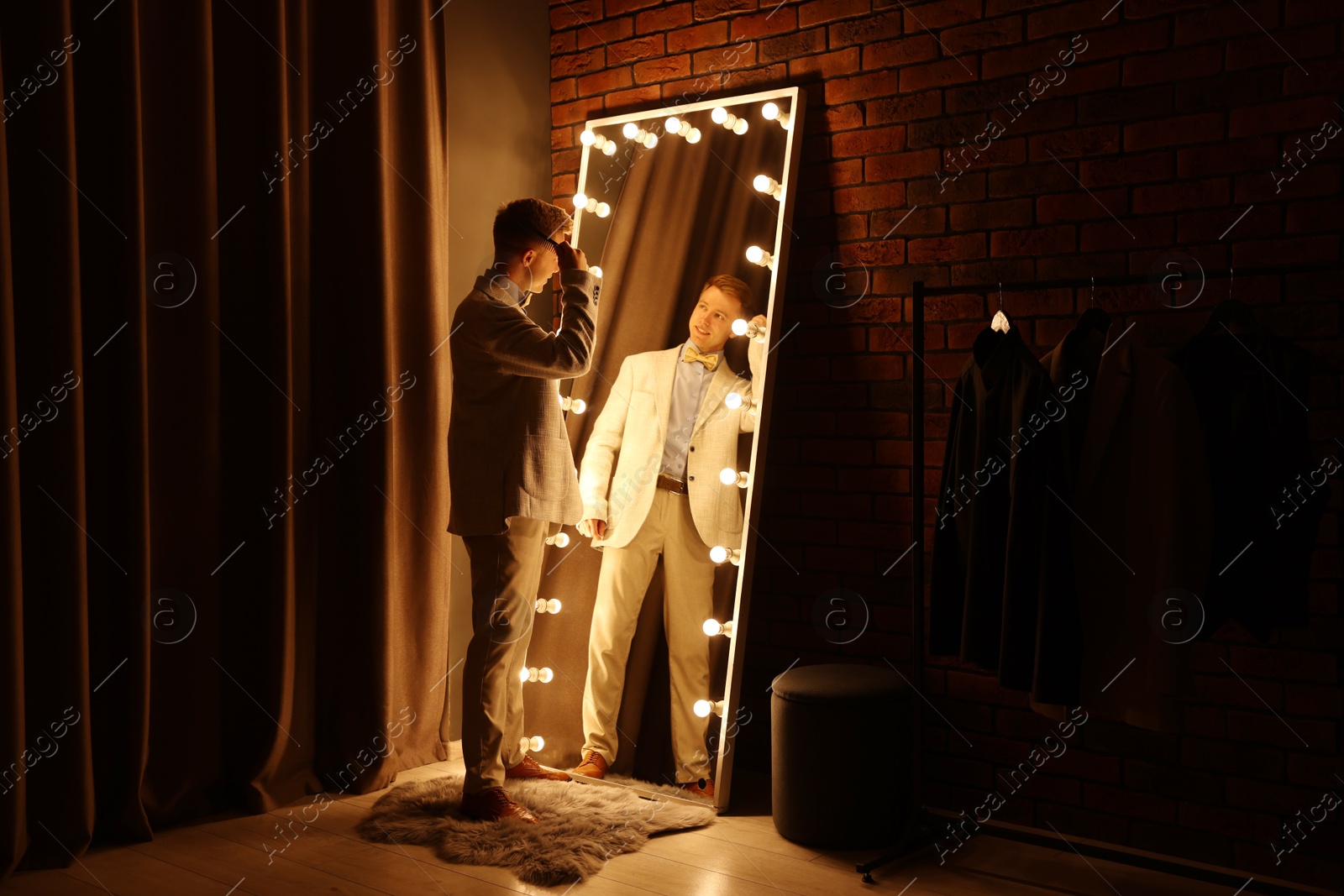 Handsome man brushing his hair while getting ready near mirror indoors Photo of Handsome man brushing his hair while getting ready near mirror indoors