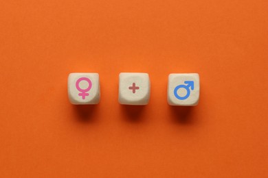 Image of Sex education. Wooden cubes with female and male gender symbols and plus sign on orange background, top view