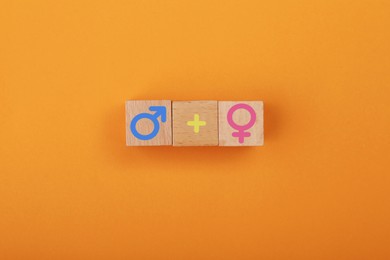 Image of Sex education. Wooden cubes with male and female gender symbols and plus sign on orange background, top view