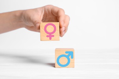 Image of Sex education. Woman putting cube with female gender symbol next to another one with male on white background, closeup