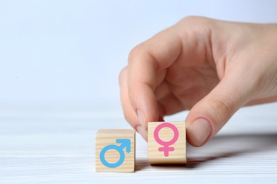 Image of Sex education. Woman putting cube with female gender symbol next to another one with male on white background, closeup