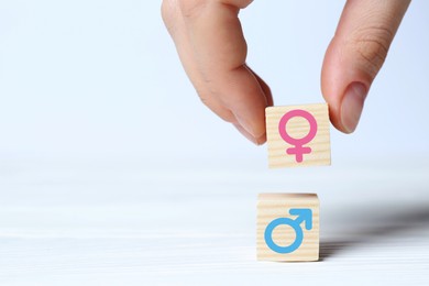 Image of Sex education. Woman putting cube with female gender symbol onto another one with male on white background, closeup