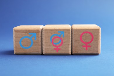 Image of Sex education. Wooden cubes with female and male gender symbols on blue background