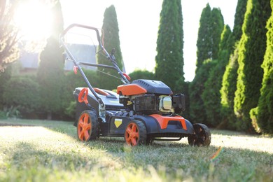 Photo of One lawn mower on green grass in garden