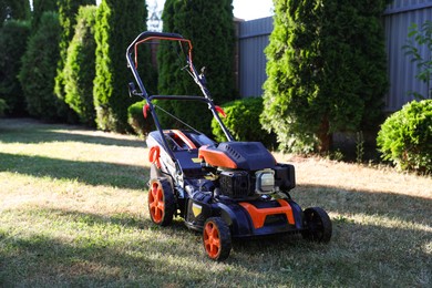 Photo of One lawn mower on green grass in garden