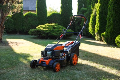 Photo of One lawn mower on green grass in garden