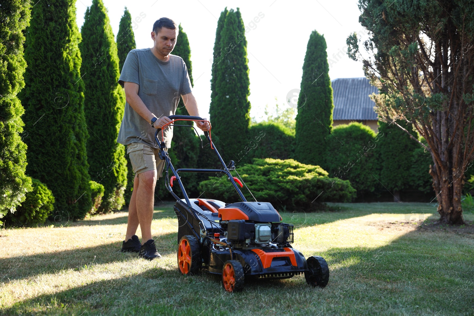 Man cutting green grass with lawn mower in garden Photo of Man cutting green grass with lawn mower in garden