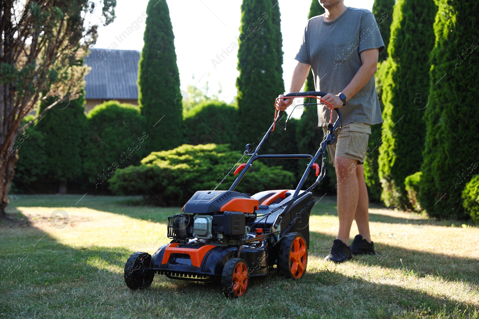 Man cutting green grass with lawn mower in garden, closeup Photo of Man cutting green grass with lawn mower in garden, closeup