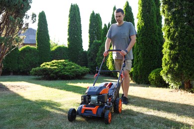 Photo of Man cutting green grass with lawn mower in garden