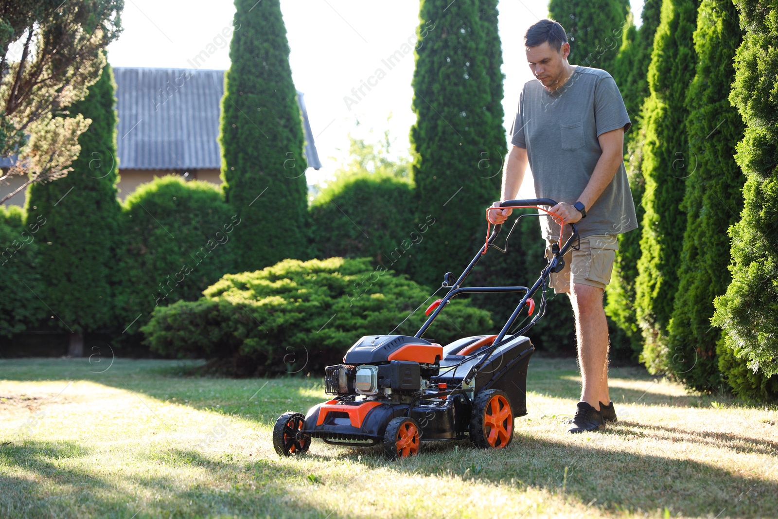 Man cutting green grass with lawn mower in garden Photo of Man cutting green grass with lawn mower in garden