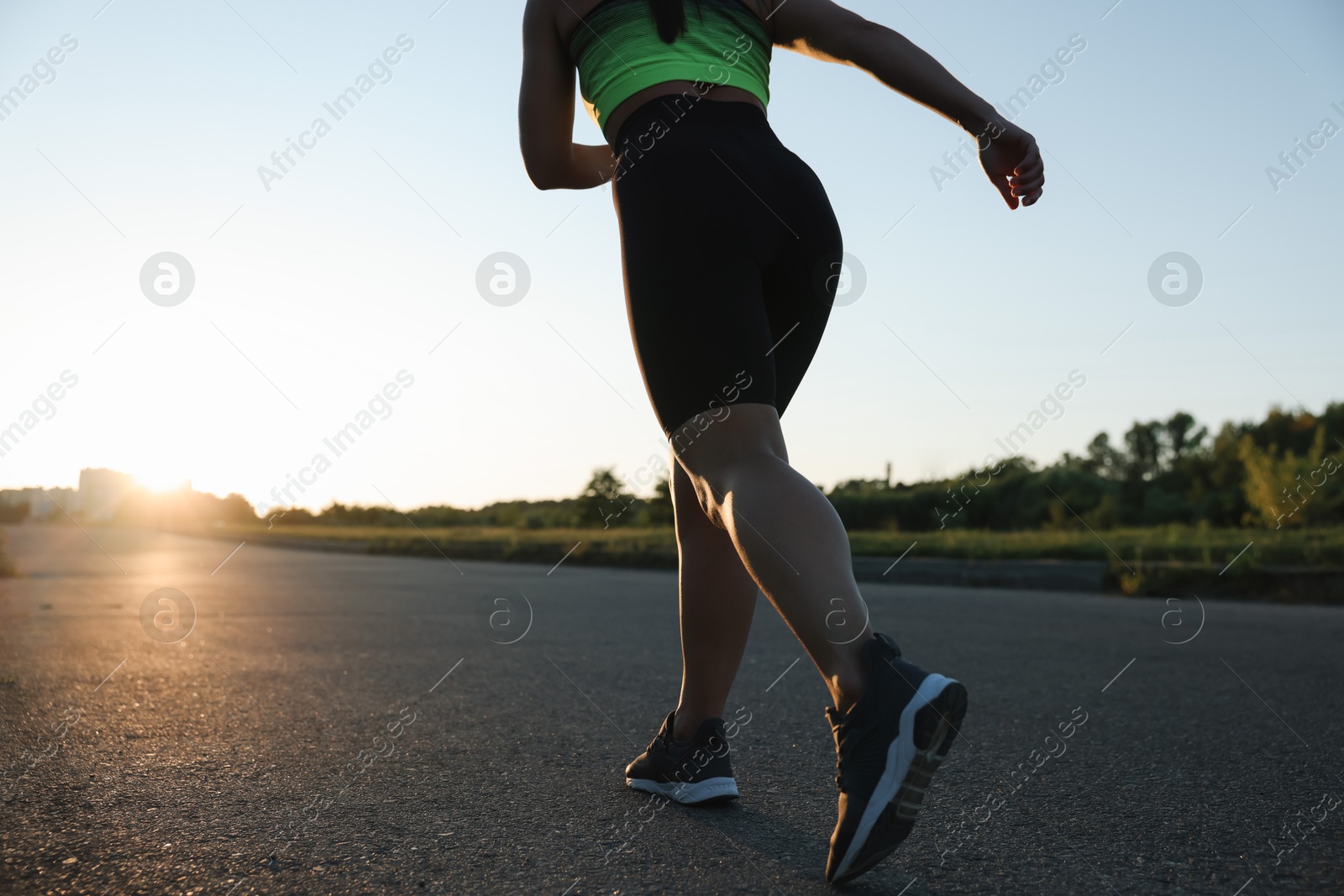 Woman in sportswear running on road outdoors, closeup. Space for text Photo of Woman in sportswear running on road outdoors, closeup. Space for text