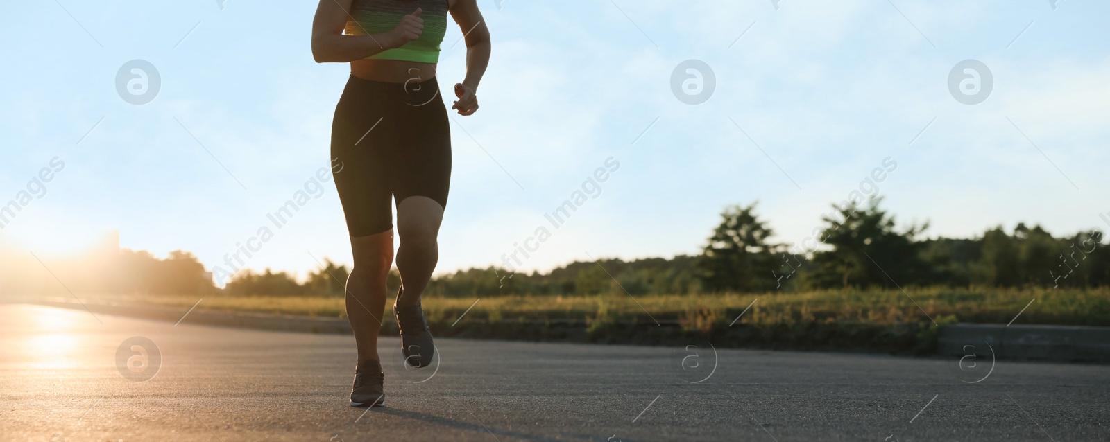 Woman in sportswear running on road outdoors, closeup. Space for text Photo of Woman in sportswear running on road outdoors, closeup. Space for text