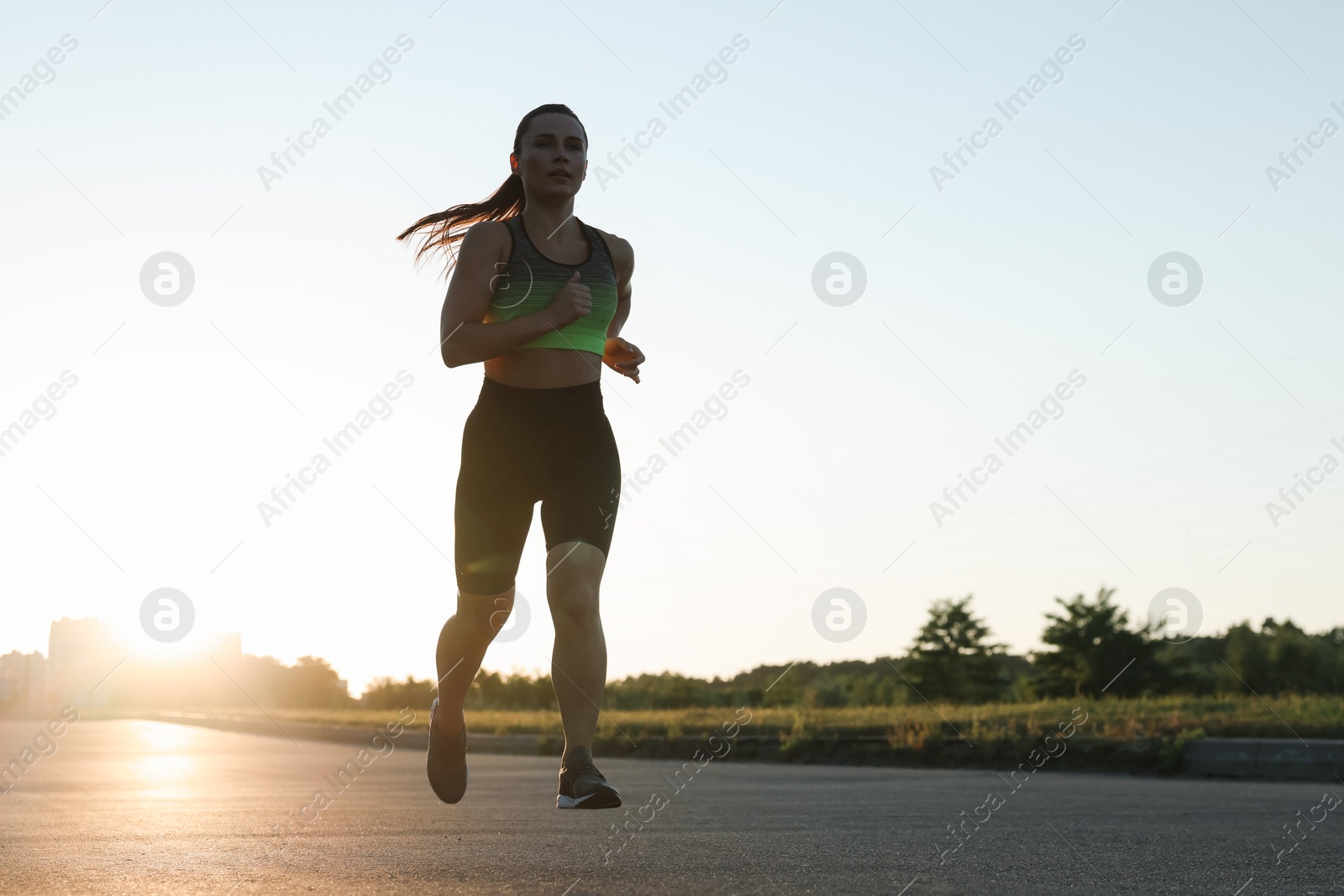 Woman in sportswear running on road outdoors, low angle view Photo of Woman in sportswear running on road outdoors, low angle view