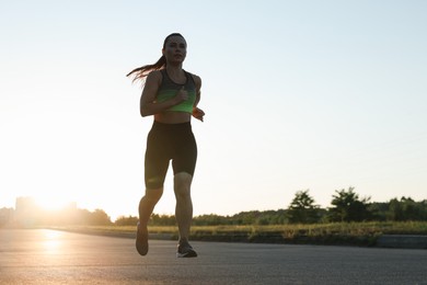 Photo of Woman in sportswear running on road outdoors, low angle view