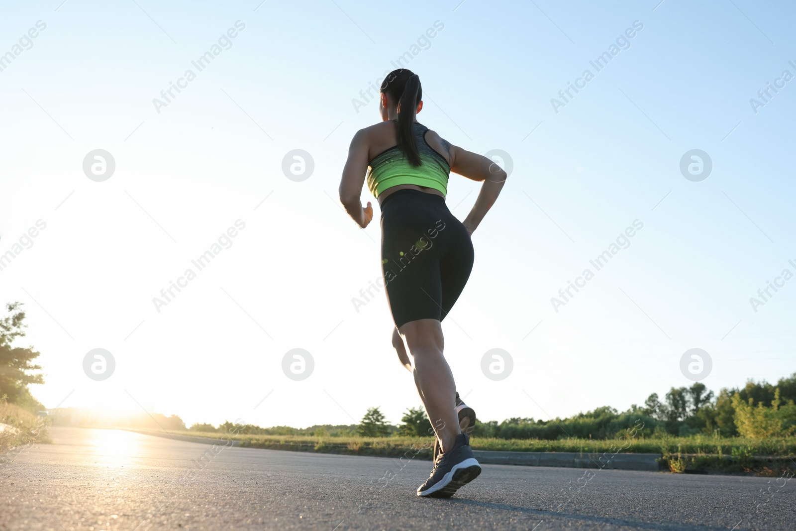 Woman in sportswear running on road outdoors, low angle view Photo of Woman in sportswear running on road outdoors, low angle view