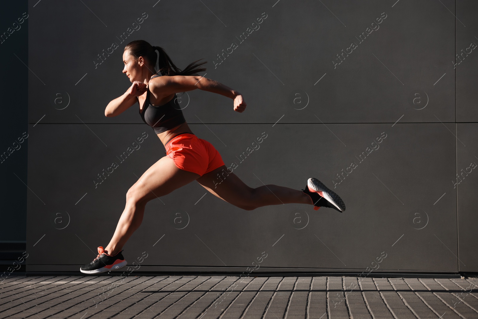 Woman in sportswear running near building outdoors Photo of Woman in sportswear running near building outdoors