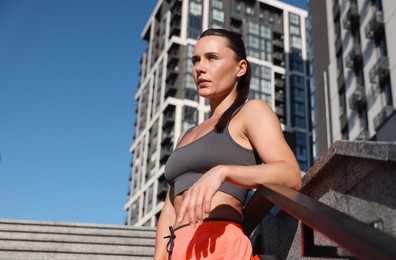 Photo of Beautiful woman in sportswear before running on stairs outdoors, low angle view