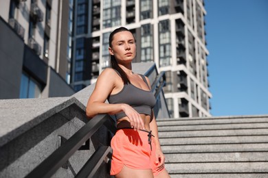 Photo of Beautiful woman in sportswear before running on stairs outdoors, low angle view
