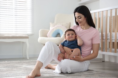 Photo of Happy mother with her cute little baby at home, space for text