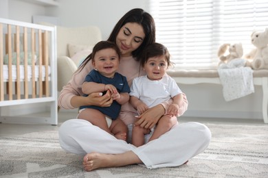 Photo of Happy mother with her cute little twin babies at home