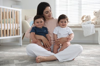Photo of Happy mother with her cute little twin babies at home