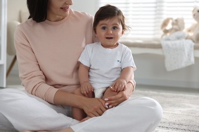 Photo of Happy mother with her cute little baby at home, closeup
