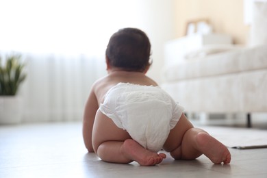 Photo of Cute little baby crawling on floor at home, back view