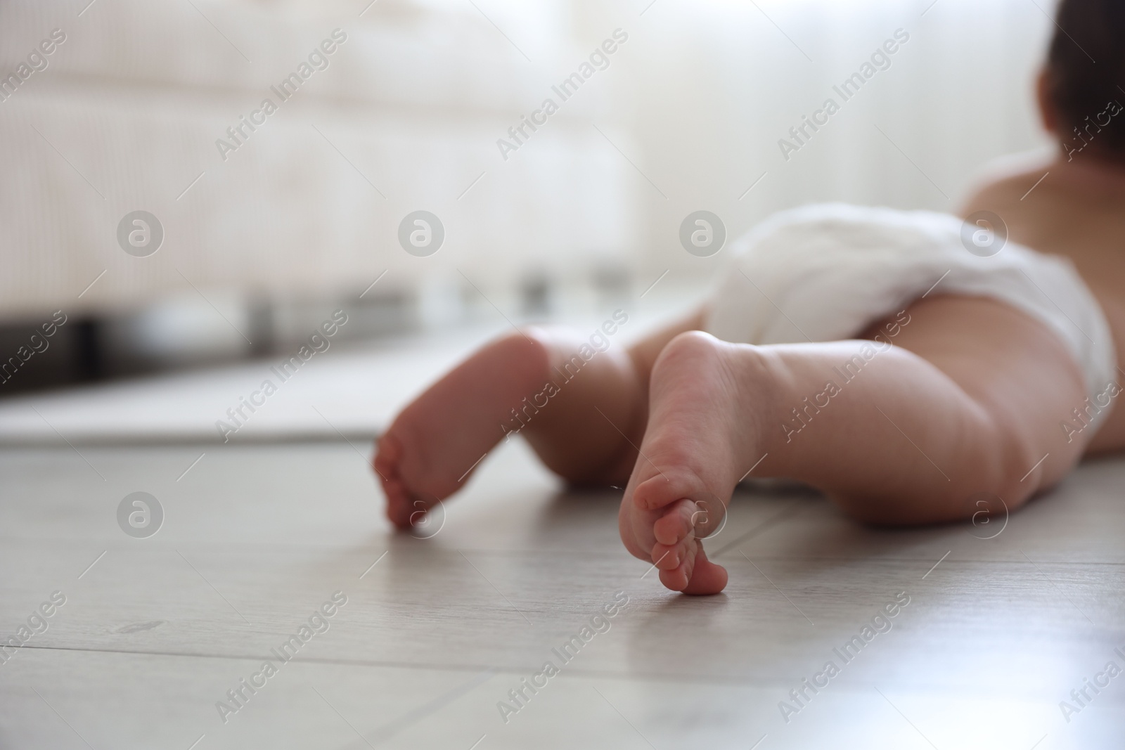 Cute little baby crawling on floor at home, selective focus Photo of Cute little baby crawling on floor at home, selective focus