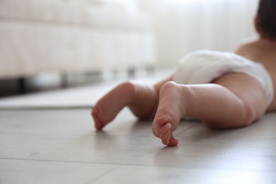 Photo of Cute little baby crawling on floor at home, selective focus