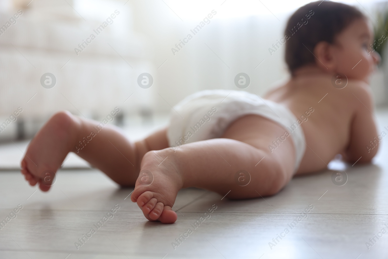 Cute little baby crawling on floor at home, selective focus Photo of Cute little baby crawling on floor at home, selective focus