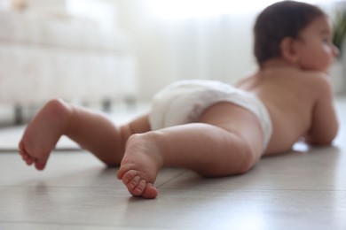 Photo of Cute little baby crawling on floor at home, selective focus