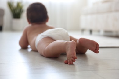 Photo of Cute little baby crawling on floor at home, selective focus