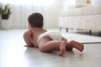 Photo of Cute little baby crawling on floor at home, selective focus