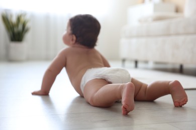 Photo of Cute little baby crawling on floor at home, selective focus