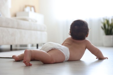 Photo of Cute little baby crawling on floor at home, selective focus