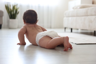 Photo of Cute little baby crawling on floor at home, selective focus