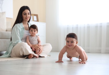 Photo of Happy mother with her cute little twin babies at home, selective focus