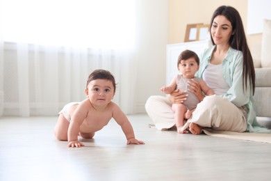 Photo of Happy mother with her cute little twin babies at home, selective focus