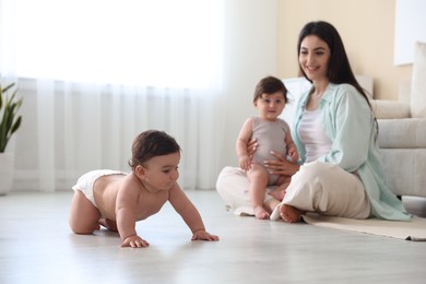 Photo of Happy mother with her cute little twin babies at home, selective focus