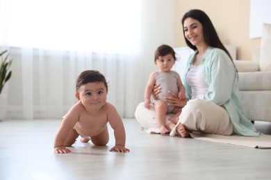 Photo of Happy mother with her cute little twin babies at home, selective focus