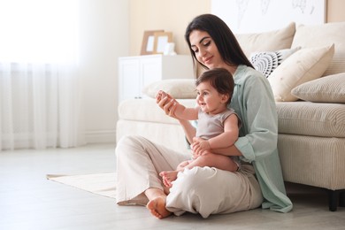 Photo of Happy mother with her cute little baby at home, space for text