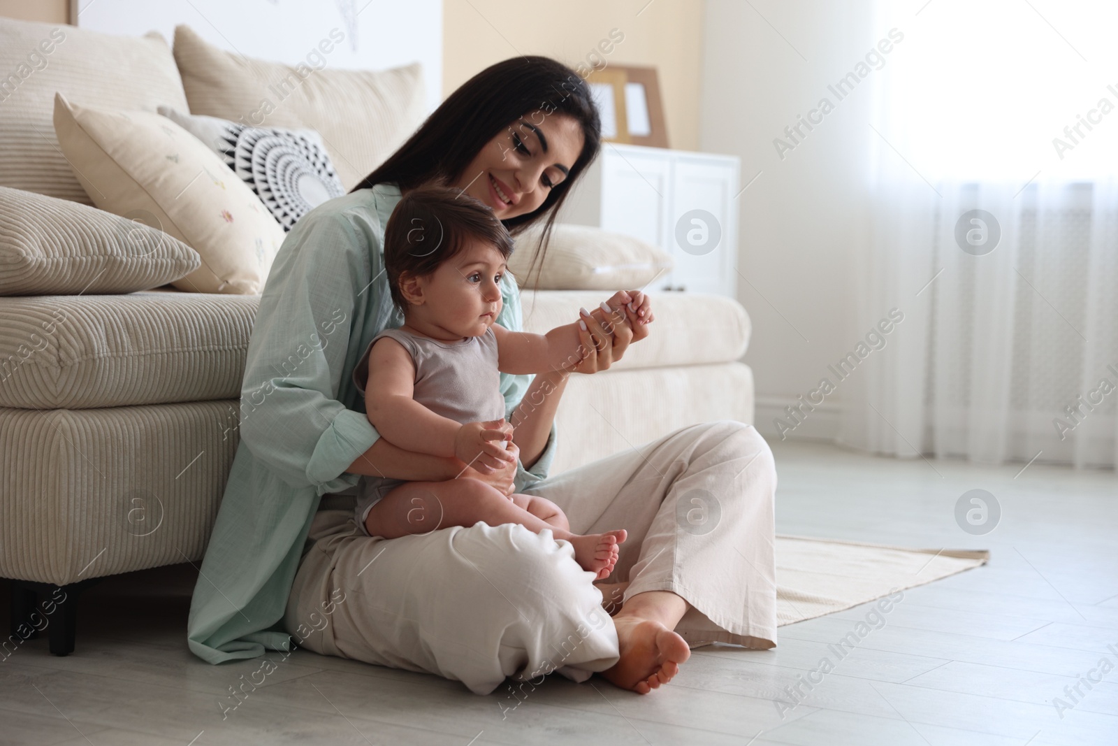 Photo of Happy mother with her cute little baby at home, space for text