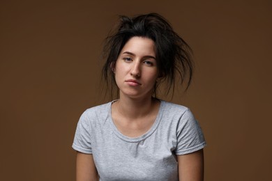 Photo of Woman suffering from hangover on brown background