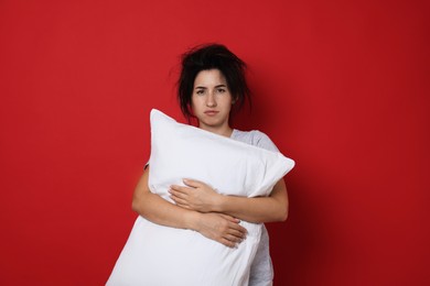 Photo of Woman with pillow suffering from hangover on red background