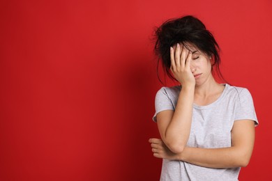 Photo of Woman suffering from hangover on red background, space for text